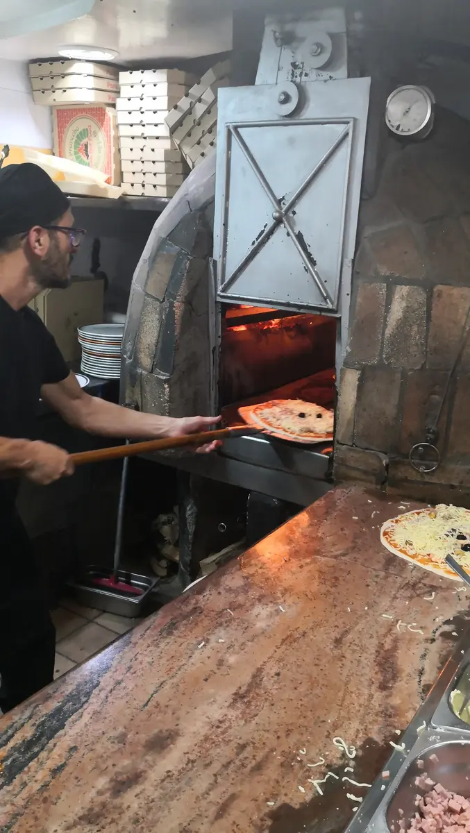 Pizza entrando en el horno de leña de Pizzería 12-34
